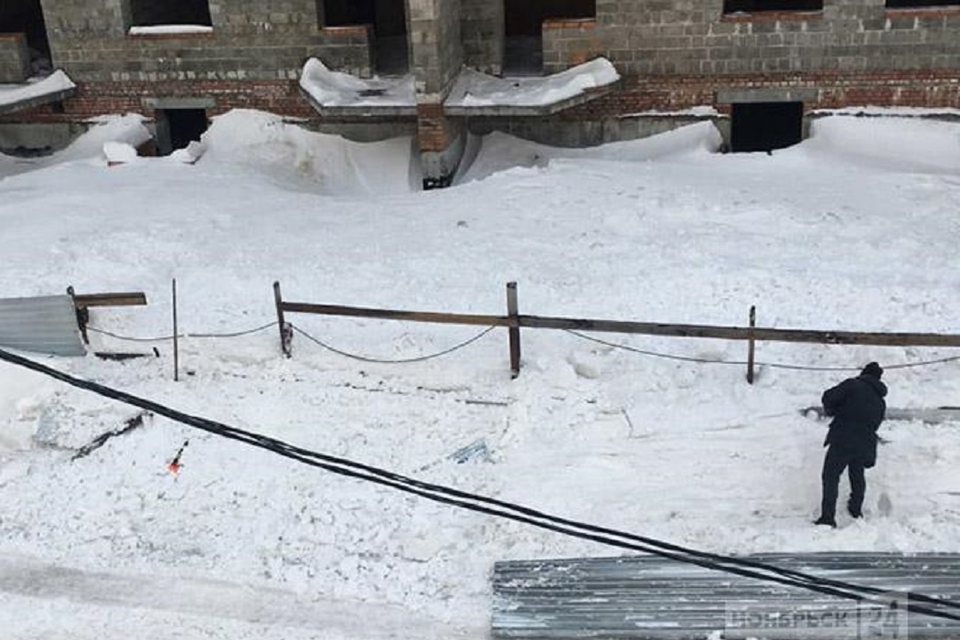 В Ноябрьске снег с крыши многоэтажки обрушил забор стройки